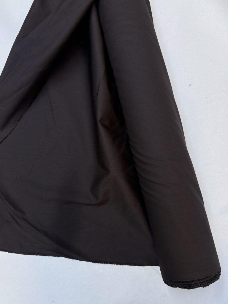 roll of brown cotton fabric in front of white background
