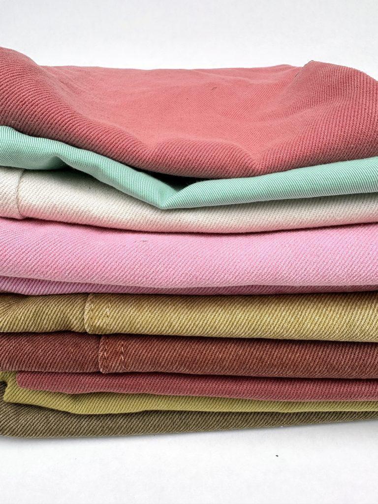 Stack of denim fabric samples in various colours